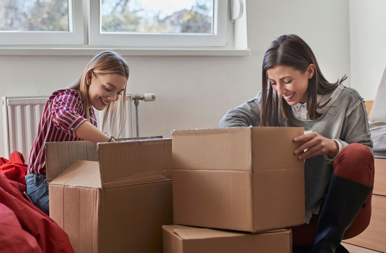 Junge Frauen packen Umzugskartons aus.