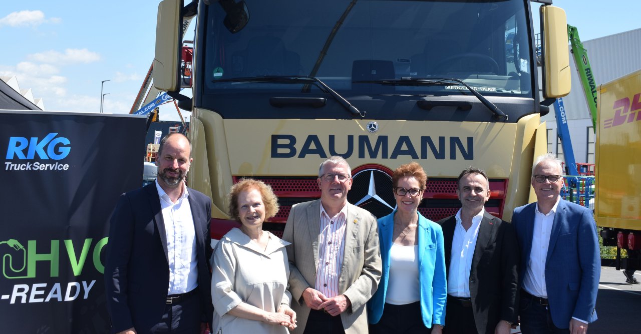 Sechs Menschen stehen vor einem LKW mit der Aufschrift Baumann.