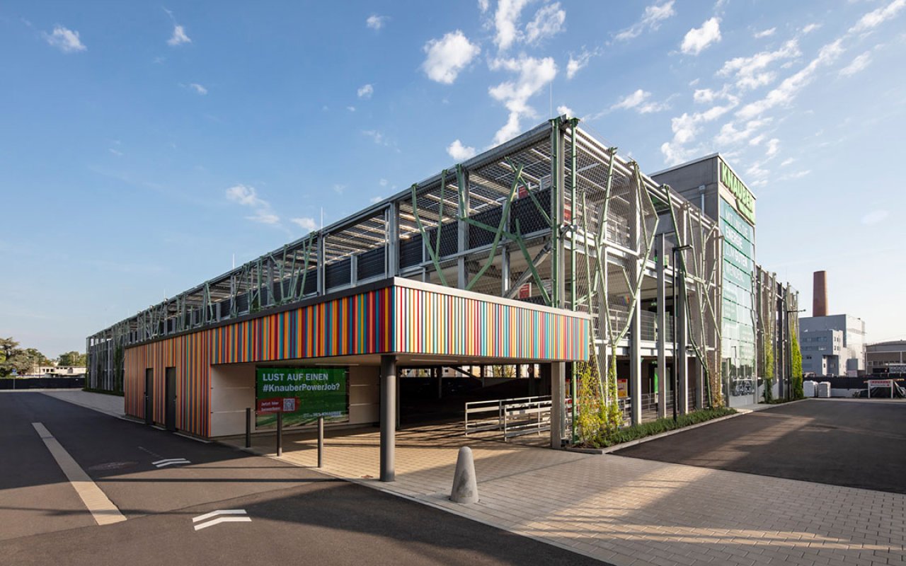 Ein modernes Parkhaus mit bunter Holzfassade vor einem blauen Himmel.