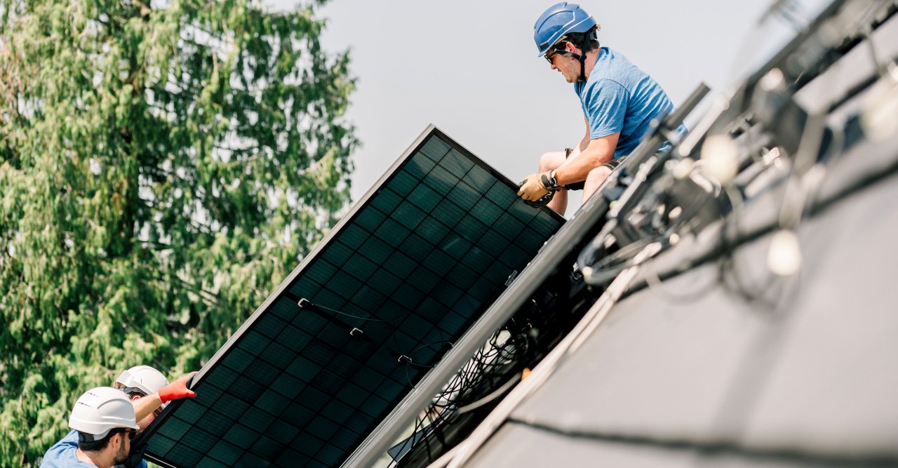 Eine PV Platte wird auf ein Dach gehoben.