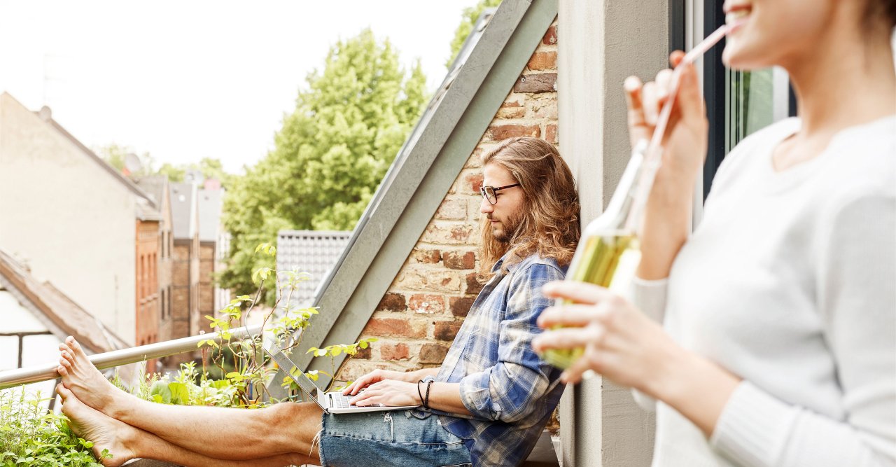 Mann sitzt auf Balkon.