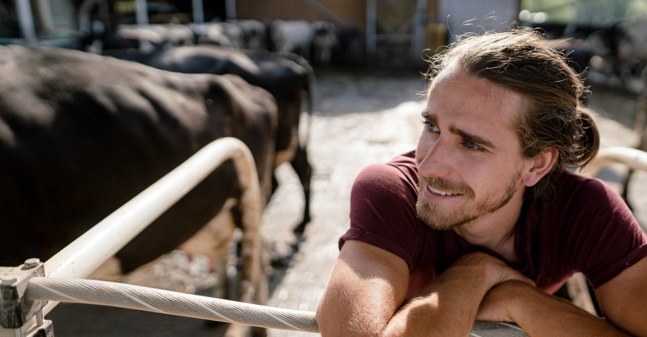 Ein junger Landwirt lehnt an einem Gatter.